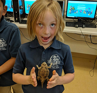 Female student standing with a bearded dragon on her chest.